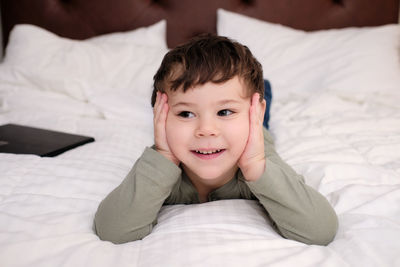 Expressive young boy watching tv on the bed in the hotel room
