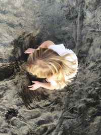 Directly above view of girl playing with sand at beach