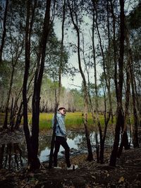 Woman standing by tree trunks in forest