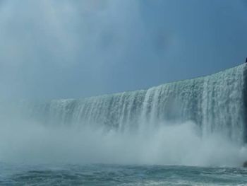 View of waterfall against blue sky