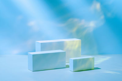 Three rectangle white podiums on pastel blue neon background