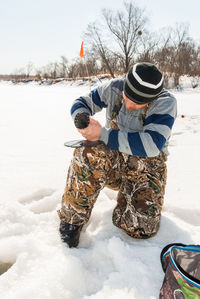 Mid adult man subglacial fishing in frozen lake