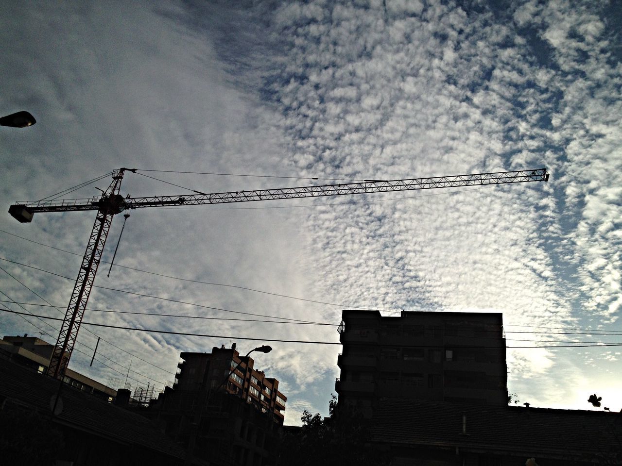 building exterior, architecture, built structure, low angle view, sky, cloud - sky, power line, silhouette, weather, crane - construction machinery, building, electricity, dusk, cloudy, outdoors, fuel and power generation, cable, construction site, no people, technology