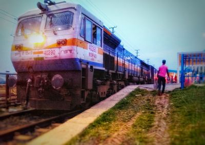 Man walking on railroad track against sky