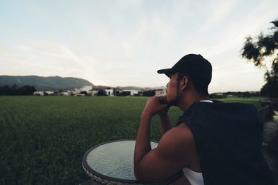 Side view of man sitting on field against mountain