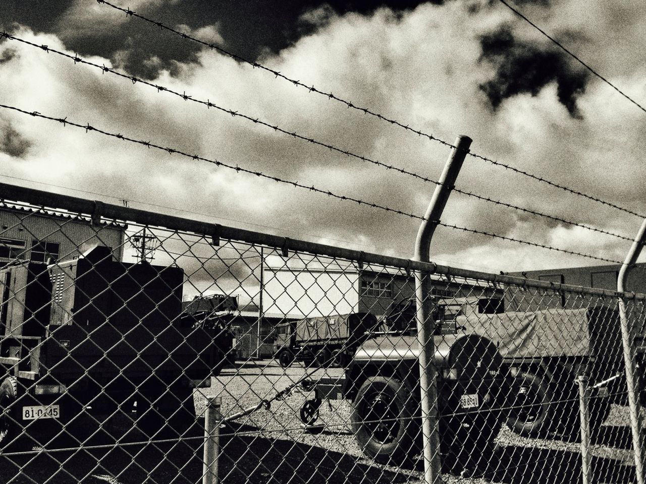 building exterior, chainlink fence, built structure, architecture, sky, fence, protection, safety, metal, cloud - sky, security, pattern, day, city, building, outdoors, men, railing, graffiti