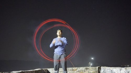 Full length of man standing against illuminated sky at night