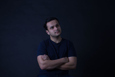 Young man day dreaming against black background