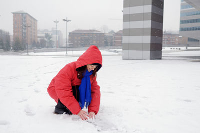 Smiling woman playing in snow during winter