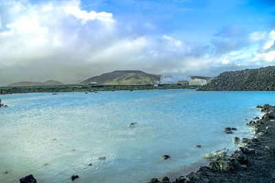 Scenic view of beach against cloudy sky