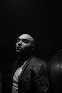 Portrait of bald young man standing in darkroom
