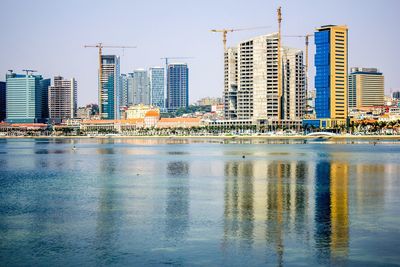 Reflection of city in water against clear blue sky