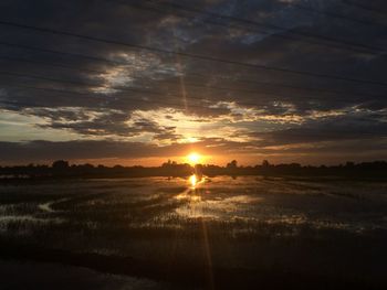 Scenic view of landscape against dramatic sky during sunset