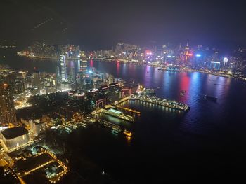 High angle view of illuminated city by sea against sky