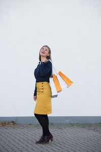 Full length of woman standing against yellow wall