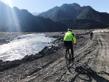 Rear view of man riding bicycle on mountain