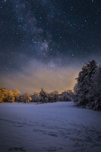 Snow covered landscape against sky at night