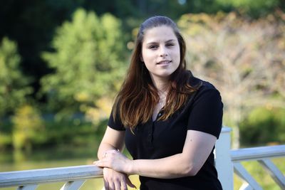 Portrait of beautiful young woman standing against trees