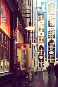 Rear view of people walking on street amidst buildings