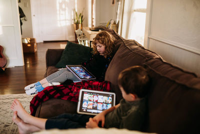 Young sister and brother watching movies on tablets while home sick