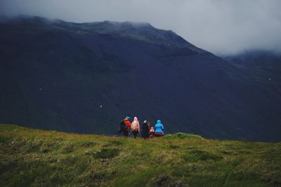 Rear view of people walking on mountain against sky
