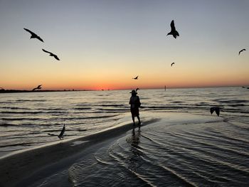 Woman standing at beach during sunset