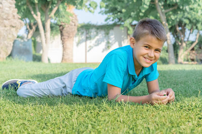 Cheerful teen boy lies on the grass in the park.