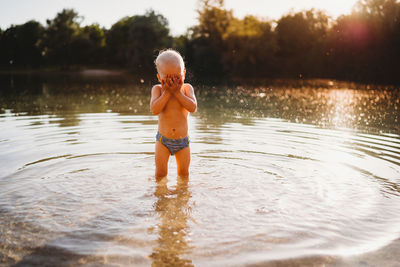 Full length of shirtless boy standing in lake