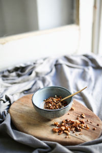 Granola in bowl on cutting board over tablecloth