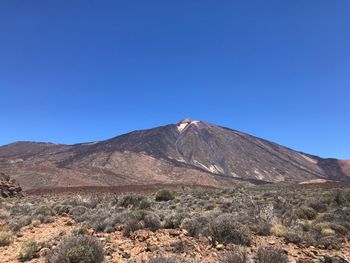 Scenic view of mountains against clear blue sky