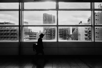 Full length of woman standing by window in city