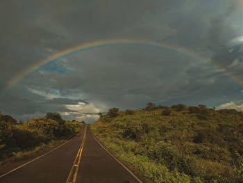 Rainbow over road against sky