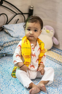Cute toddler baby boy sitting at bed at home