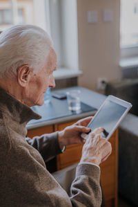 Man holding mobile phone while sitting on table