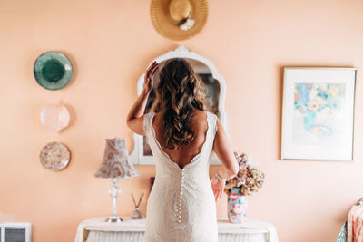 Young woman standing against wall at home