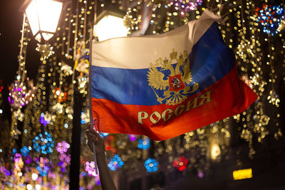 Low angle view of illuminated flags hanging on tree at night