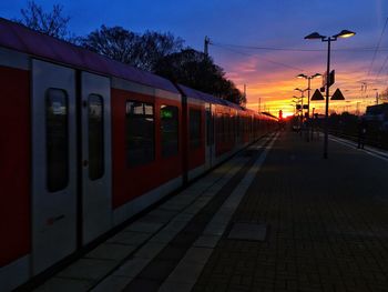 Road by railroad station against sky at sunset