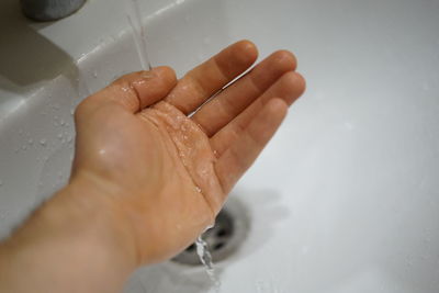 Cropped image of person hand touching water in bathroom