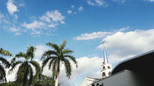 Low angle view of church by palm trees against sky