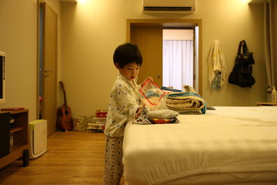 Side view of boy standing in bedroom at home