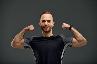 Portrait of young man standing against black background