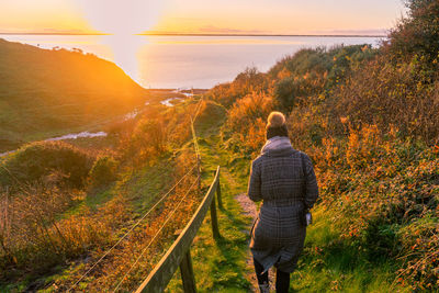 Rear view of woman looking at view during sunset