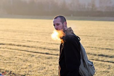 Portrait of man smoking on field during winter 