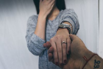 Cropped image of man holding woman hand