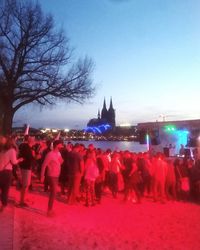 Silhouette of people at riverbank against clear sky