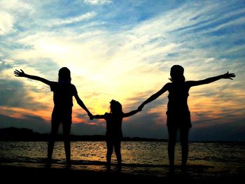 Silhouette people on beach against sky during sunset