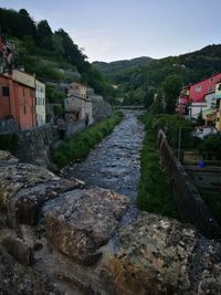 Houses by river against sky