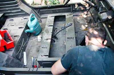 Rear view of mechanic repairing vehicle in workshop