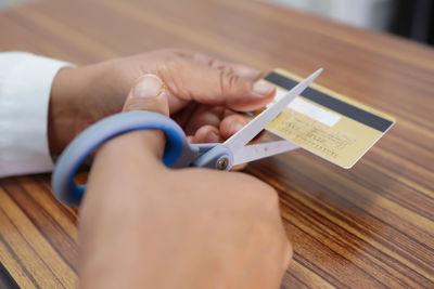 Close-up of hand holding paper with text on table