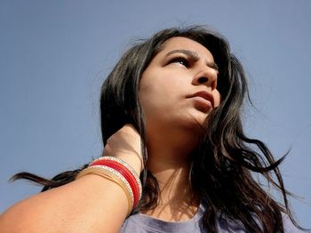 Portrait of a beautiful young woman against sky